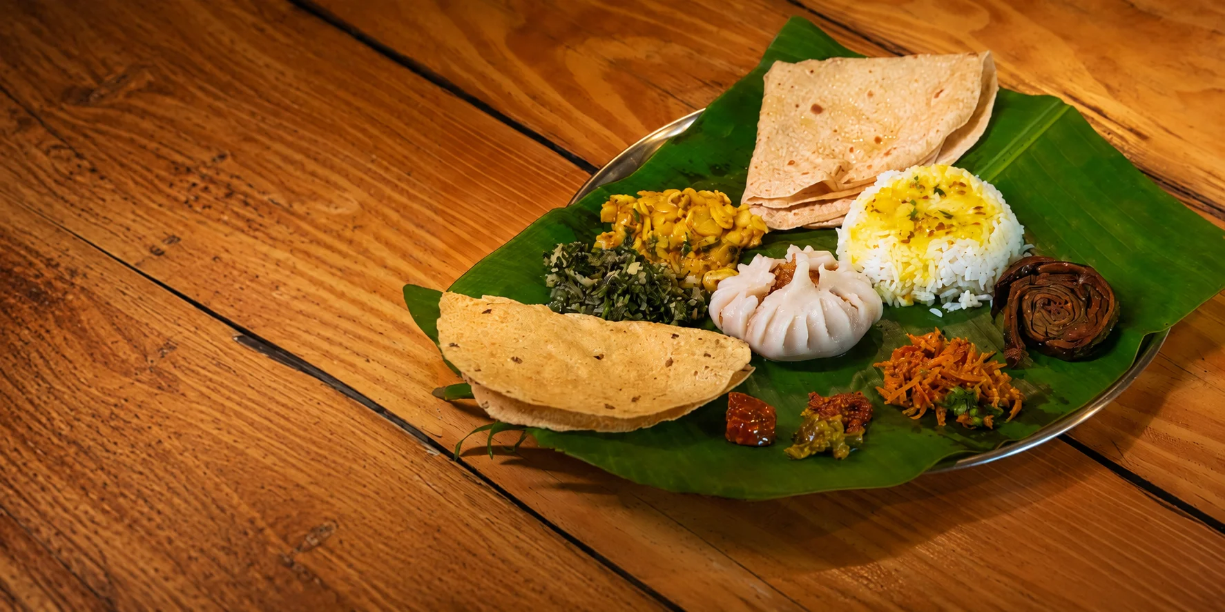 A Konkani thali on a banana leaf: modak, rice, usal, chapati and pickles
