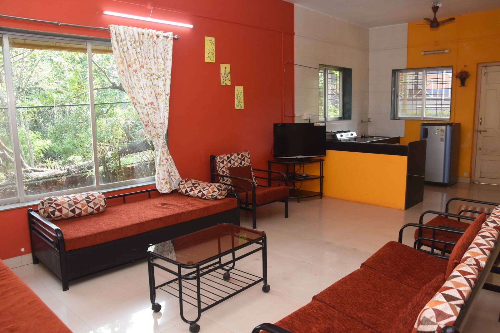 Living room with sofa-cum-beds, TV and open kitchen with fridge, Nakshatra Holiday Home Dapoli